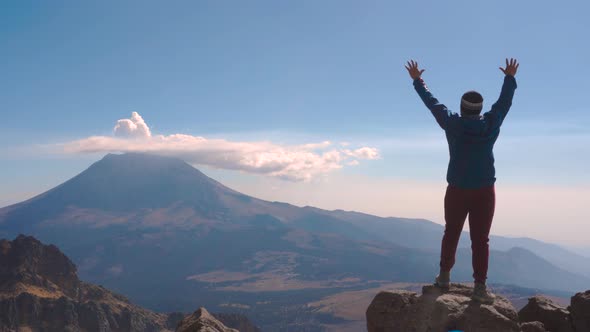 Young man standing on the edge of a cliff on top of the iztaccihuatl volcano with magnificent views