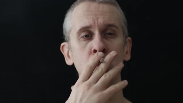 Caucasian Man Smoking a Cigarette on a Black Background