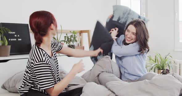 Two friends at home having a pillow fight