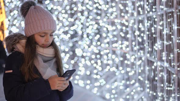 Teen Girl Using Smartphone Outdoors at Christmas Time