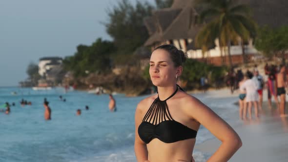 Young Beautiful Woman Stands on Exotic Beach and Looks Into the Distance Sunset