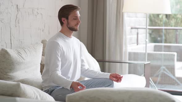 Mindfulness and Calm Mood Young Man Sits on a Sofa in the Living Room and Meditates a Calm Mood