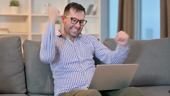 Successful Young Man Celebrating on Laptop at Home 