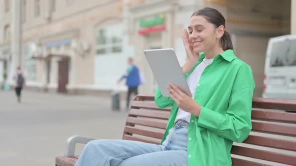 Online Video Chat on Tablet By Hispanic Woman Sitting Outdoor on Bench