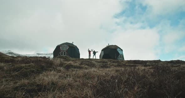 Couple dancing between two houses with mountains as a backdrop