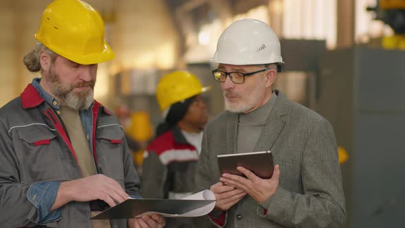 Senior Engineer and Technician Using Tablet and Talking in Plant