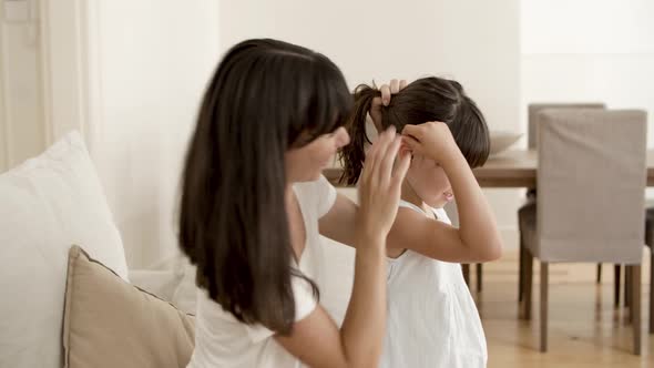 Cheerful Mom Gathering Daughters Hair in Bun