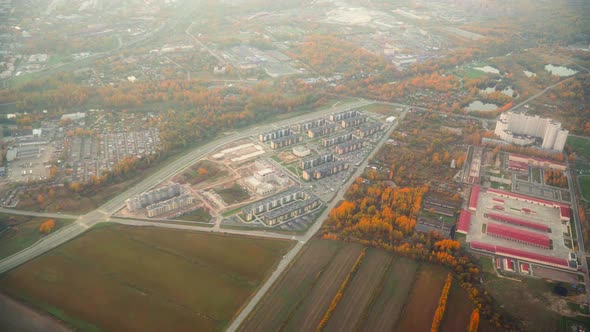 Drone shot out of a propeller plane during a flight above a village or a small town, during a sunset