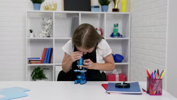 Curious Teen Girl Looking Through Microscope on Biology Lesson School