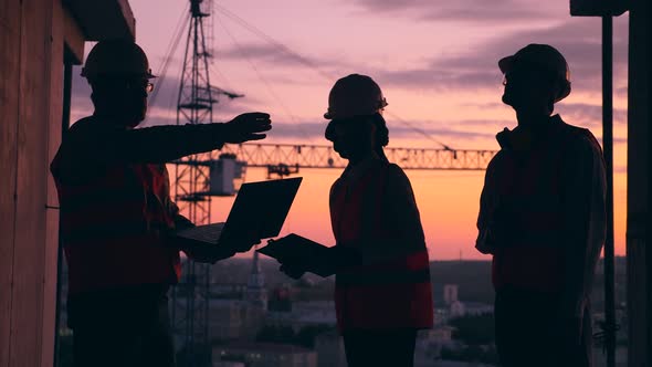 Group of Engineers Are Talking at the Sunset Building Site alt