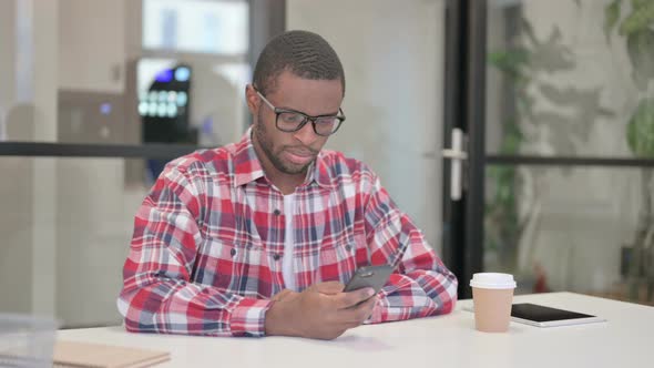 Attractive African Man Using Smartphone in Office