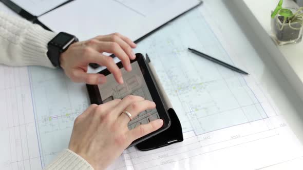 The business team works with construction drawings using a tablet.