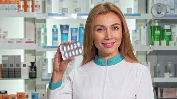 Female Pharmacist Smiling Holding Blister of Capsules at Drugstore