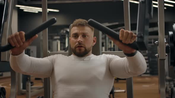 Strong Muscular Man Doing Biceps Exercises on the Exercise Machine