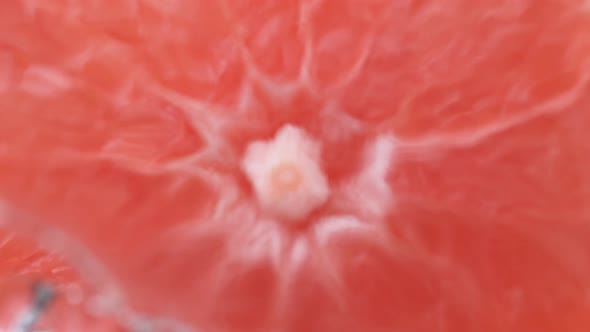 Water splash on halved pink grapefruit. Slow Motion.