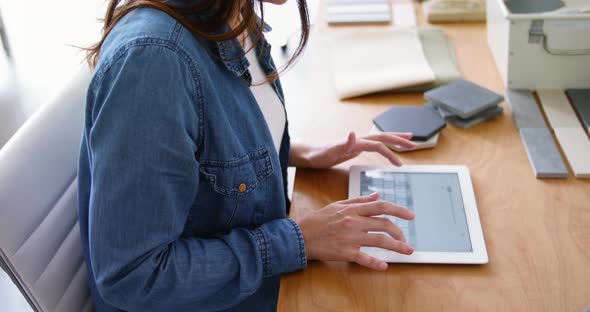 Female executive sitting at desk and using digital tablet