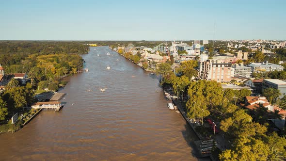 Aerial dolly in of Tigre rowing club and amusement park beside de la Plata River surrounded by trees