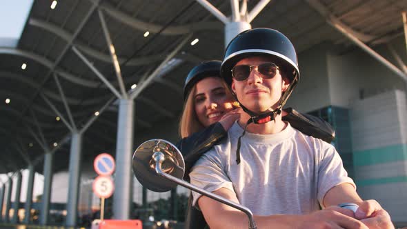 Happy Young Couple Riding Vintage Scooter on Urban Background and Having Some Fun Slow Motion