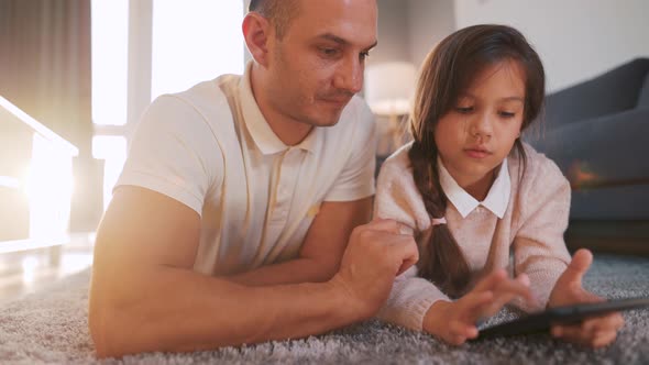 Happy Father and Daughter Enjoying Time Together and Using a Tablet for Family Entertainment While