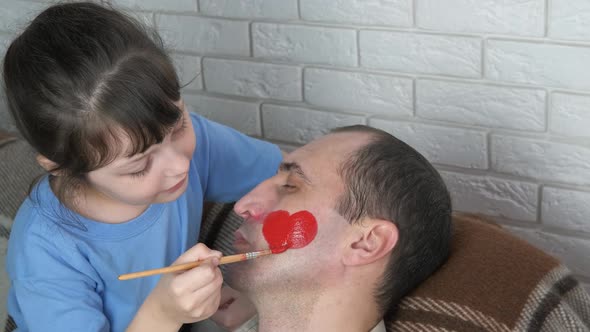 Child draw on face. A pretty happy child draw father's face. 