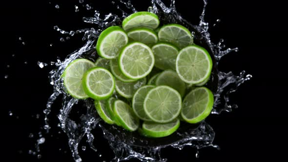 Super Slow Motion Shot of Rotating Exploded Lime Slices with Splashing Water on Black at 1000Fps