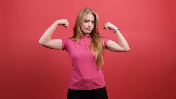 Young Woman Points To the Strong Hands on a Red Background