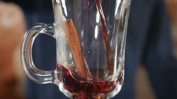 Hot Mulled Wine with Spices Being Poured Into Transparent Glass. Slow Motion. Glintwein Pouring Into