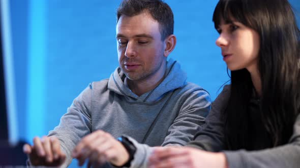 Handsome Smiling Man Talking with Beautiful Woman Indoors Typing on Computer Keyboard