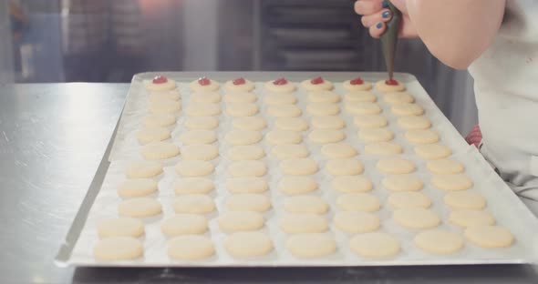 Baker preparing butter cookies with strawberry jam and powdered sugar