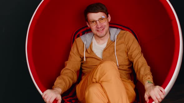 Handsome Man in Glasses Sitting in Round Chair