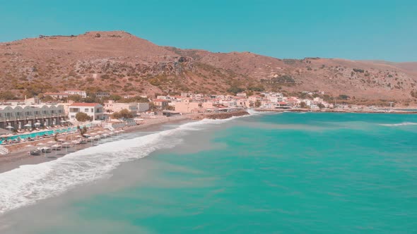 Drone flying past a small Greek town with mountain in background.