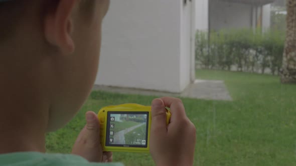 Child with camera making photos during rainy day