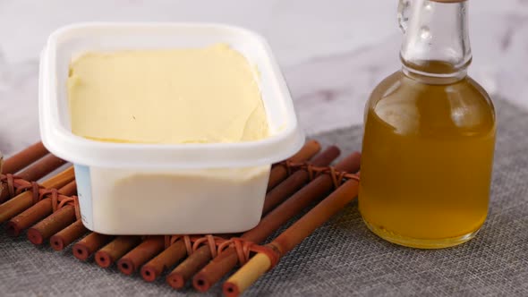 Fresh Butter in a Container with Bread on White Background