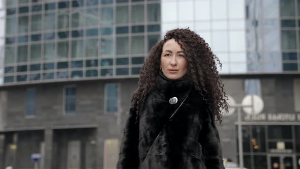 Confident Stylish Lady Is Wearing Fur Coat Is Walking in Modern City Medium Portrait