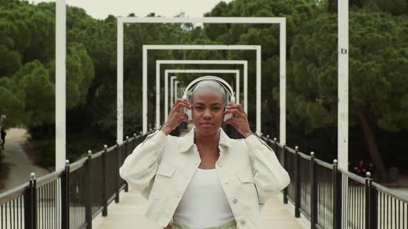 Slow motion shot of woman listening to music standing on a bridge