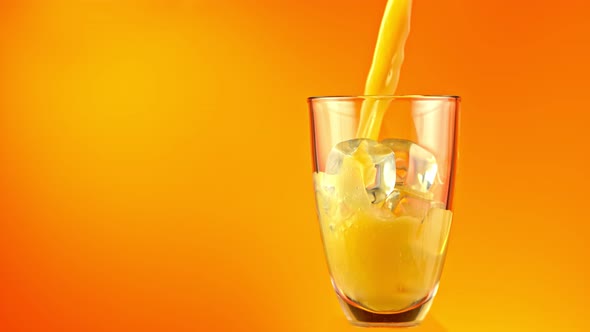 Super Slow Motion Shot of Pouring Fresh Orange Juice Into Glass with Ice Cubes at 1000 Fps