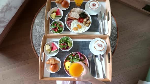 From Above of Woman Hand Serve Breakfast in Hotel and Put Glass of Orange Juice