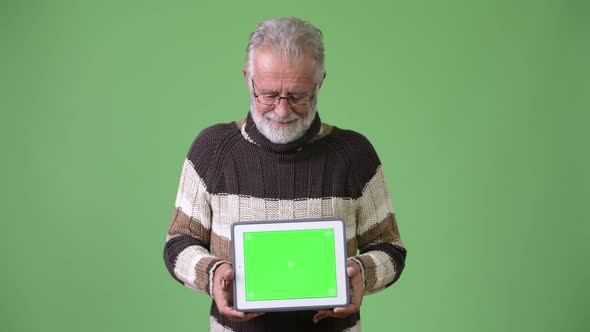 Handsome Senior Bearded Man Wearing Warm Clothing Against Green Background