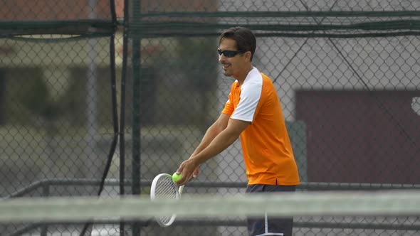 Male tennis player serving during match.