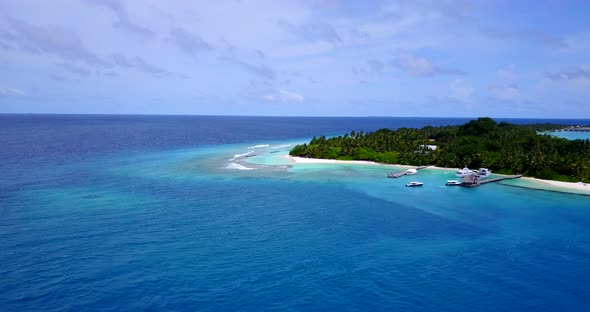 Daytime overhead tourism shot of a white paradise beach and blue ocean background in hi res 4K