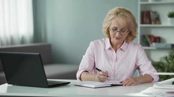 Mature Woman Creating Shopping List, Writing Plans in Notepad, Busy Housewife