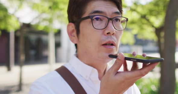 Close up of asian man talking on smartphone while standing on the street