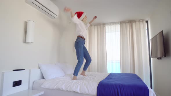 slender beautiful girl dancing in a Santa Claus hat on the bed.