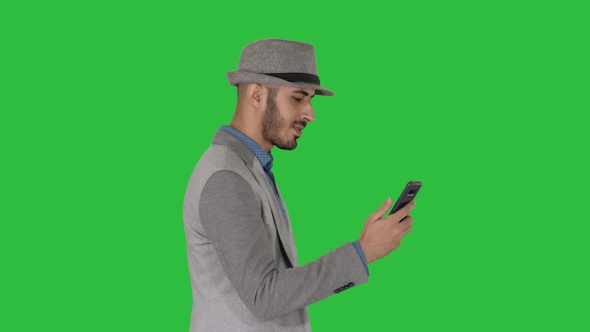 Man walking with a phone and serfing internet on a Green