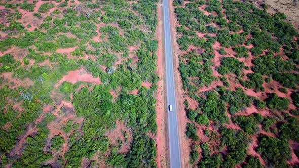 Isolated Asphalt Road With Traveling Safari Vehicle In Kenya, East Africa. Aerial Drone Shot