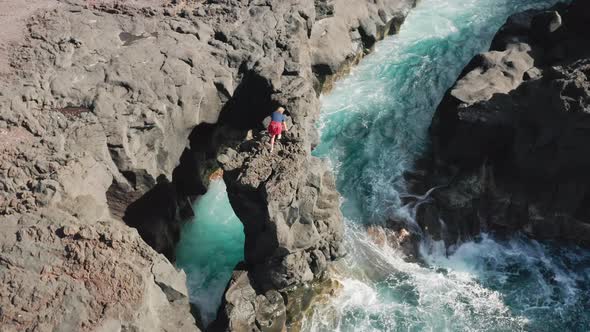 Tourist Explores Rocky Cliff Within the Atlantic