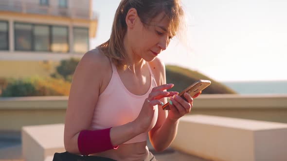 Close Up of Attractive Young Adult Sportswoman Use Smartphone Outdoor