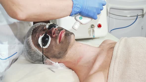 Man Getting Facial Carbon Peeling at Beauty Clinic By Professional Cosmetologist