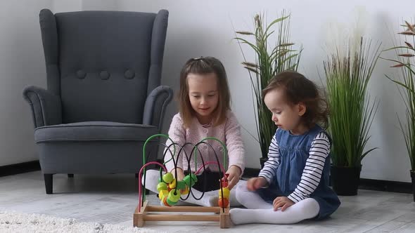 Two beautiful sisters play with a multicolored toy (Montessori technique)