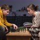 A young man teaches his girlfriend to play chess at home in the evening - VideoHive Item for Sale